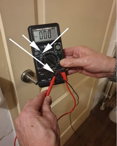 Digitale multimeter op de ohm-stand, met pijlen naar de meetstand en de twee meetpennen