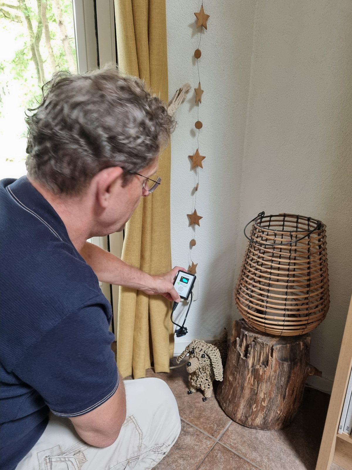 Erik meet elektromagnetische velden bij een stopcontact. Medium-foto van een meting in huis, relevant voor MemonizerCOMBI en bescherming tegen elektrosmog van de elektrische installatie.