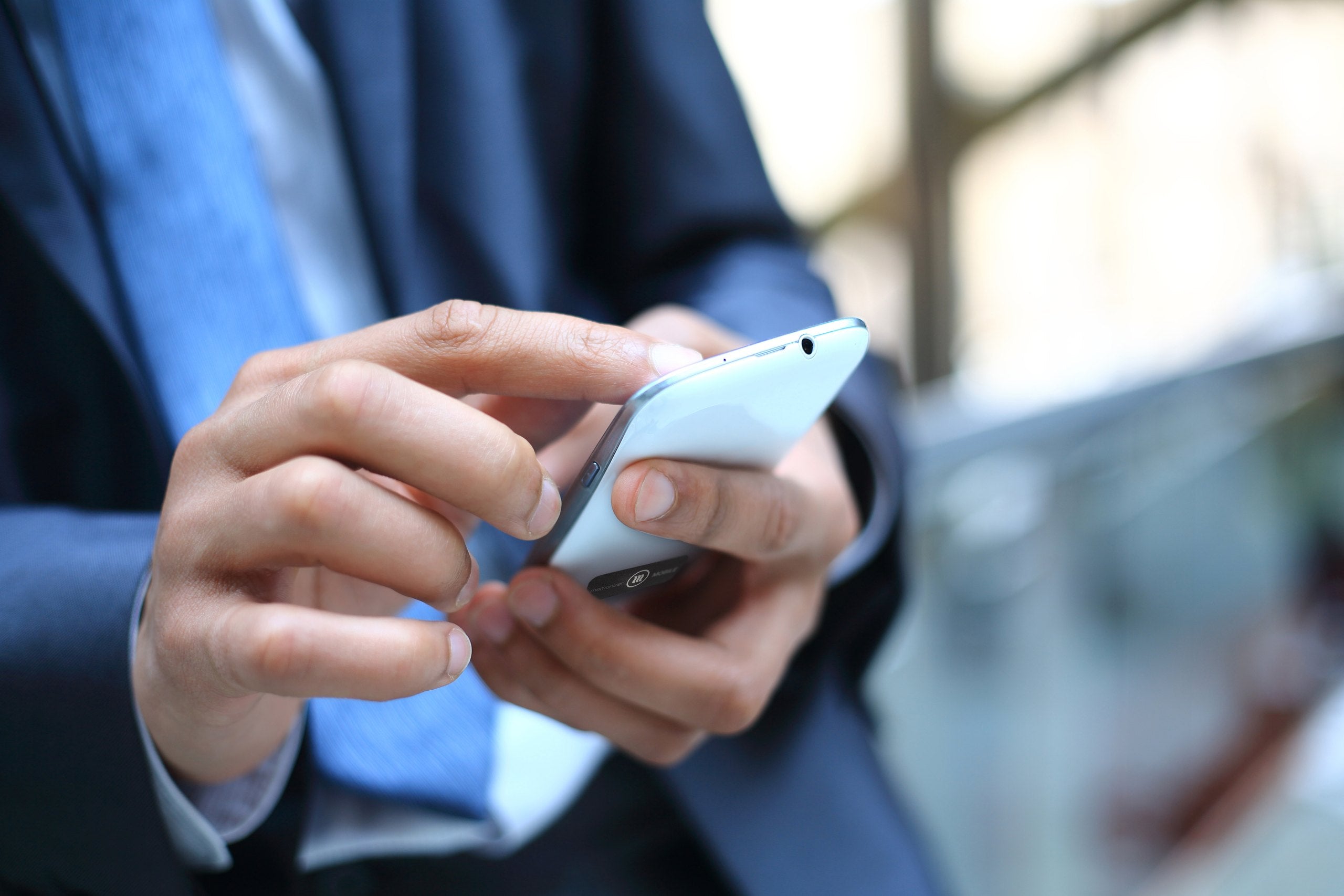 Man in pak houdt een smartphone in zijn hand, de plek waar de MemonizerMOBILE op komt
