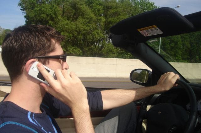 Man belt met zijn mobiele telefoon tegen zijn oor terwijl hij autorijdt