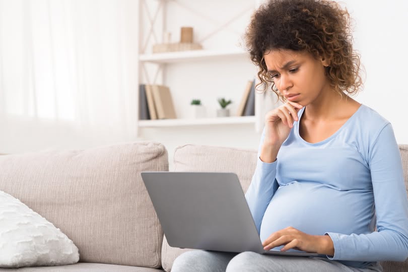 Zwangere vrouw met een laptop op schoot, vlak boven haar buik, een bron van straling