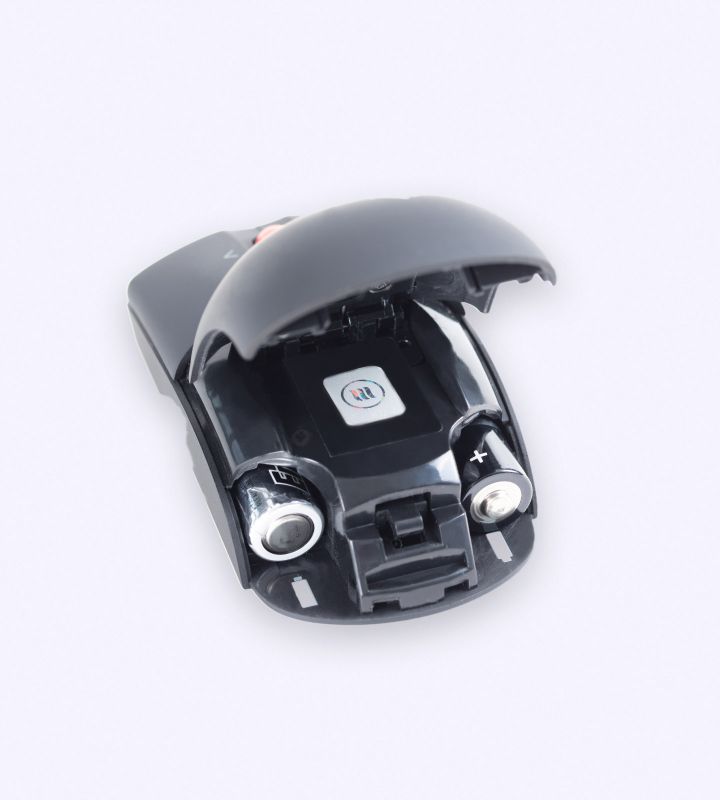 Open batterijvak van een draadloze muis met twee batterijen en een memonizerWIRELESS-sticker erin.